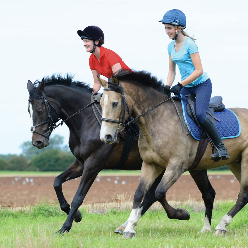 lady and girl cantering across the countryside